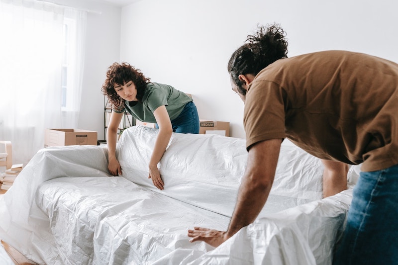 A couple wrapps up an antique couch as they prepare to move